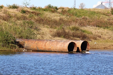 Storm drain pipes emptying water into a coastal estuary viewed from side