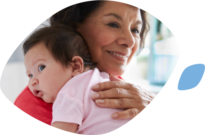 Mother gazes lovingly at her toddler while the little girl looks forward at the camera