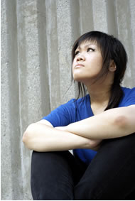 Young lady sitting down and looking up longingly