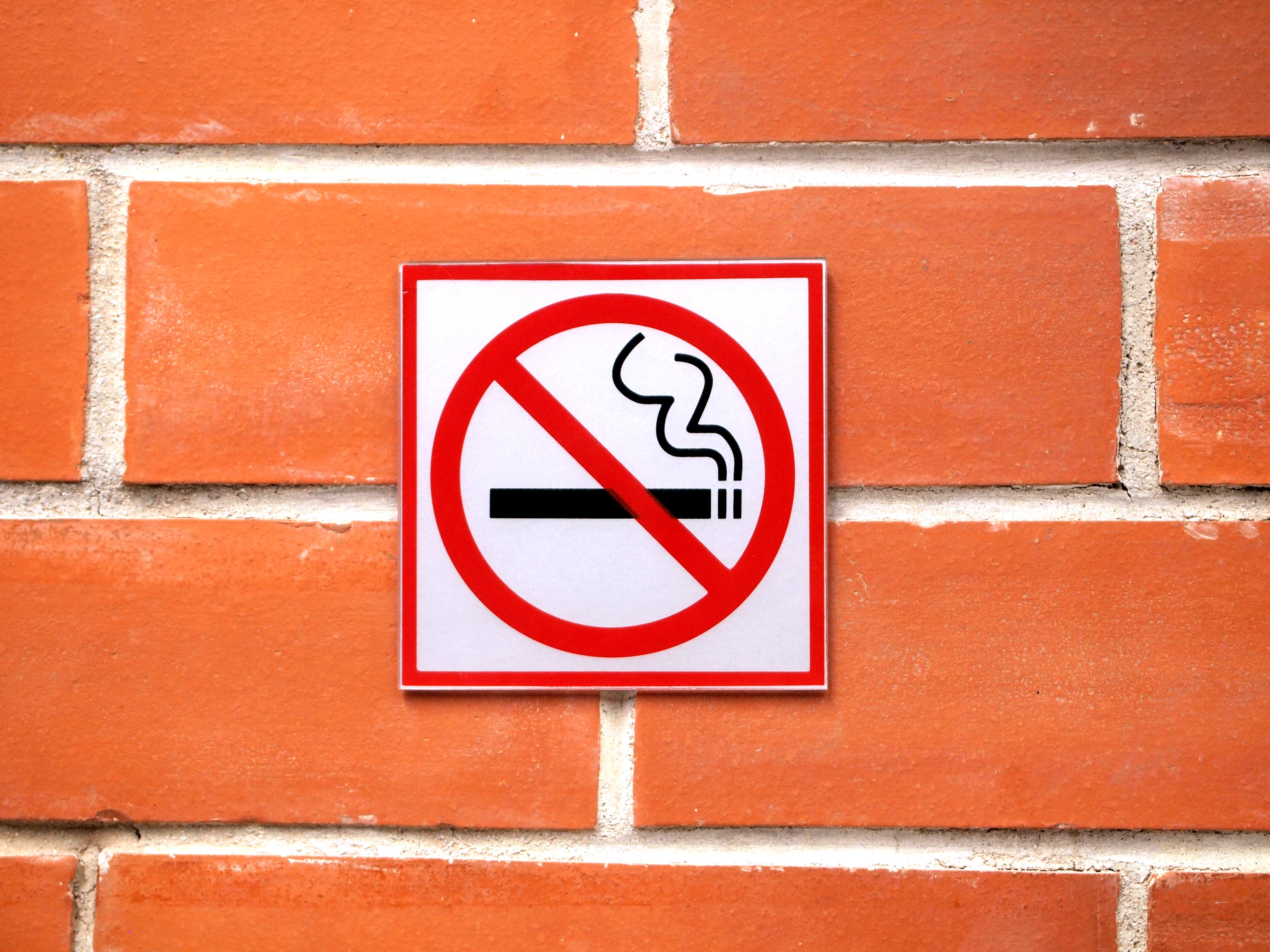 A No smoke sign placed on a brick wall