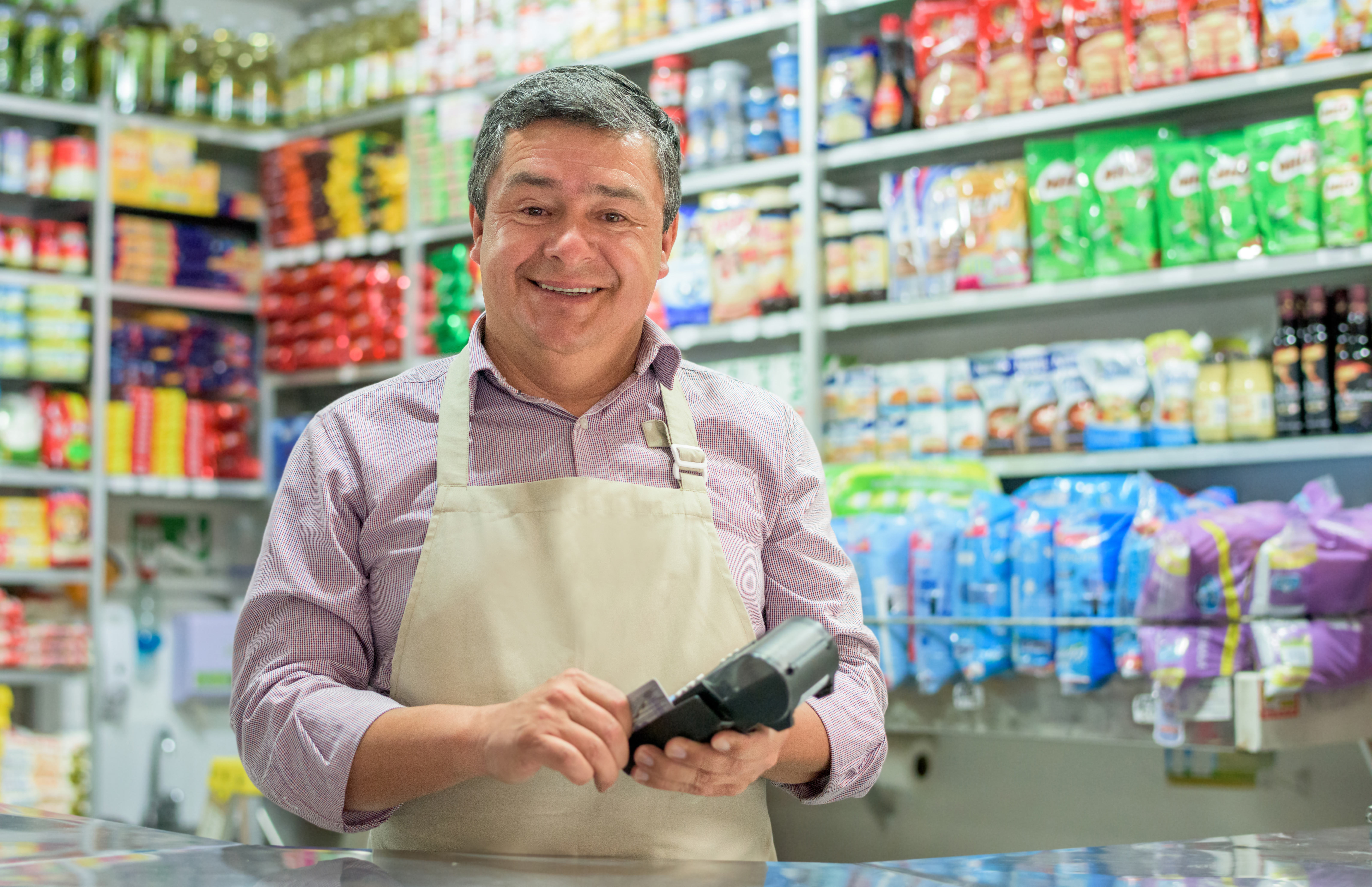 A vendor holding a card reader in his shop