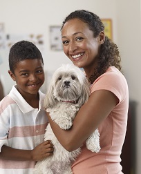Picture of children petting dog on the sofa with parent